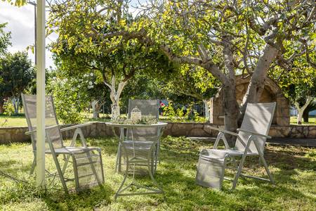 Villa Ganios, Blick durch blühende Sträucher auf die weitläufige, grüne Gartenanlage des Hotels.