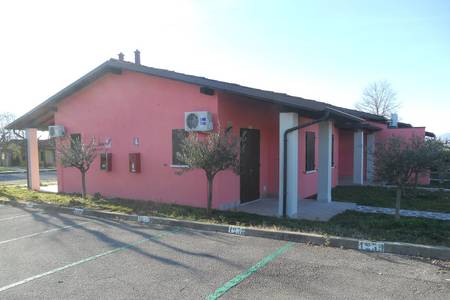 The Garda Village, Reihe von modernen Bungalows in einer gepflegten Gartenanlage unter blauem Himmel.
