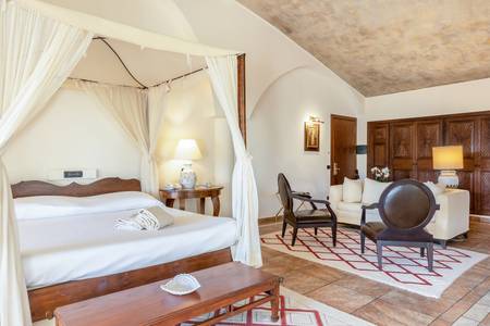 Hotel Costa dei Fiori, Schlafbereich einer Suite mit hochwertigen Textilien.