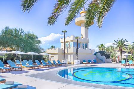 Minareto, Außenpool der Anlage mit Liegestühlen und Blick auf die Küste.