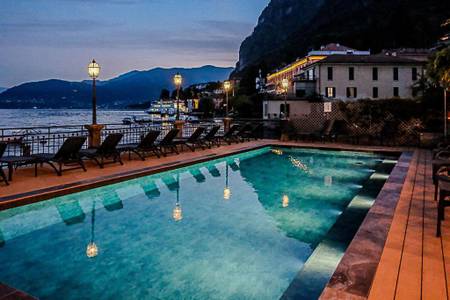 Hotel Bellavista, Beleuchteter Hotelpool bei Nacht mit Blick auf das glitzernde Meer im Hintergrund.
