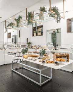 Hospes Puerta de Alcalá, Liebevoll angerichteter Frühstückstisch mit Kaffeetassen, frischen Brötchen, Aufschnitt und Obst in hellem Ambiente.