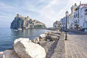 Am Ufer von Ischia mit Felsen und Häusern und Burg auf Berg Italien