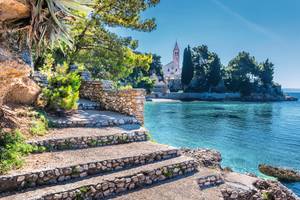 Steintreppen am türkisblauem Meer mit dem Kloster im Hintergrund auf Brac Kroatien