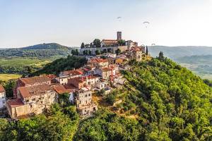 Motovun, das auf einem Berg liegt, von oben und Blick auf die umliegende Landschaft und Gleitschirmspringer am Himmel