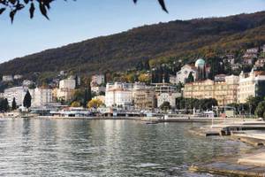 Küste von Opatija mit Häusern an der Promenade und bewaldetem Hügel dahinter