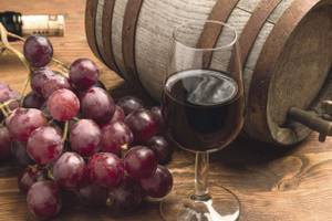 rote Trauben, Rotweinglas und ein kleines Holzfass Piemont Norditalien