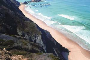 Costa Vicentina von oben mit Sandstrand, schwarzen Klippen und türkisblauem Meer