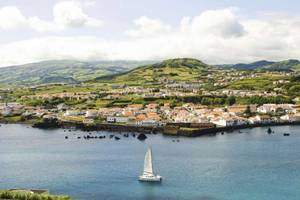 Blick vom Meer auf Horta auf Faial mit wolkenverhangenen Bergen im Hintergrund