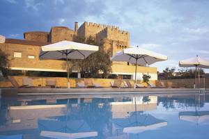 Pousada in Portugal mit Sonnenschirmen am Pool und Gebäude mit Burg im Hintergrund