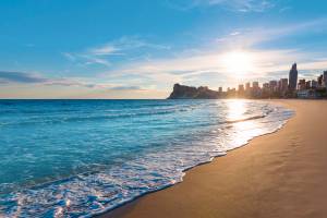 Strand in Valencia mit klarem Wasser und der Stadt im Hintergrund bei Sonnenschein