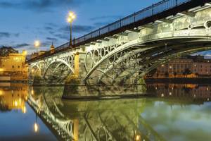 Triana Brücke in Sevilla, die sich im Wasser spiegelt bei Abendstimmung